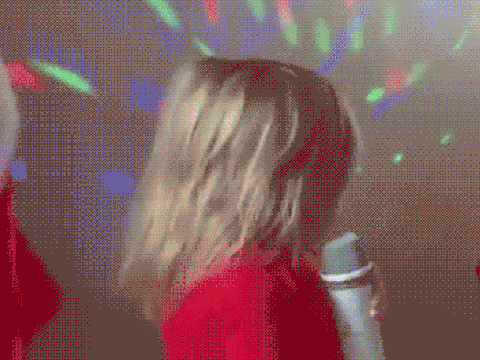 Little girl with a microphone with colorful lights in the background.