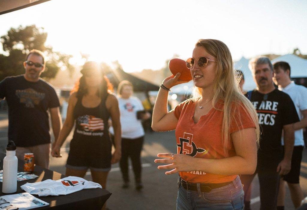 An SDSU Student throwing a football at a tailgate at the Viejas Arena.